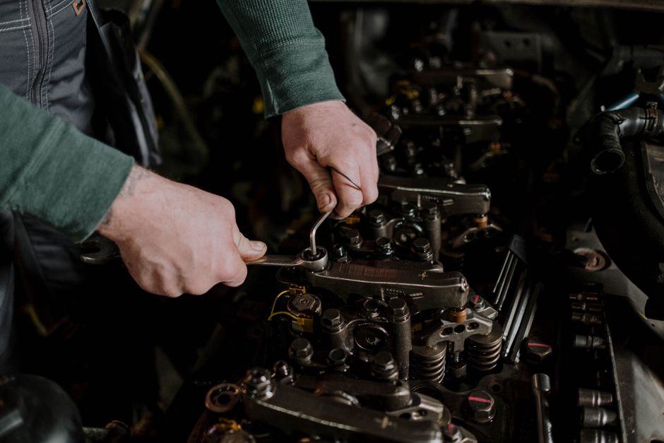Mains d'un mécanicien réglant une culasse de moteur diesel
